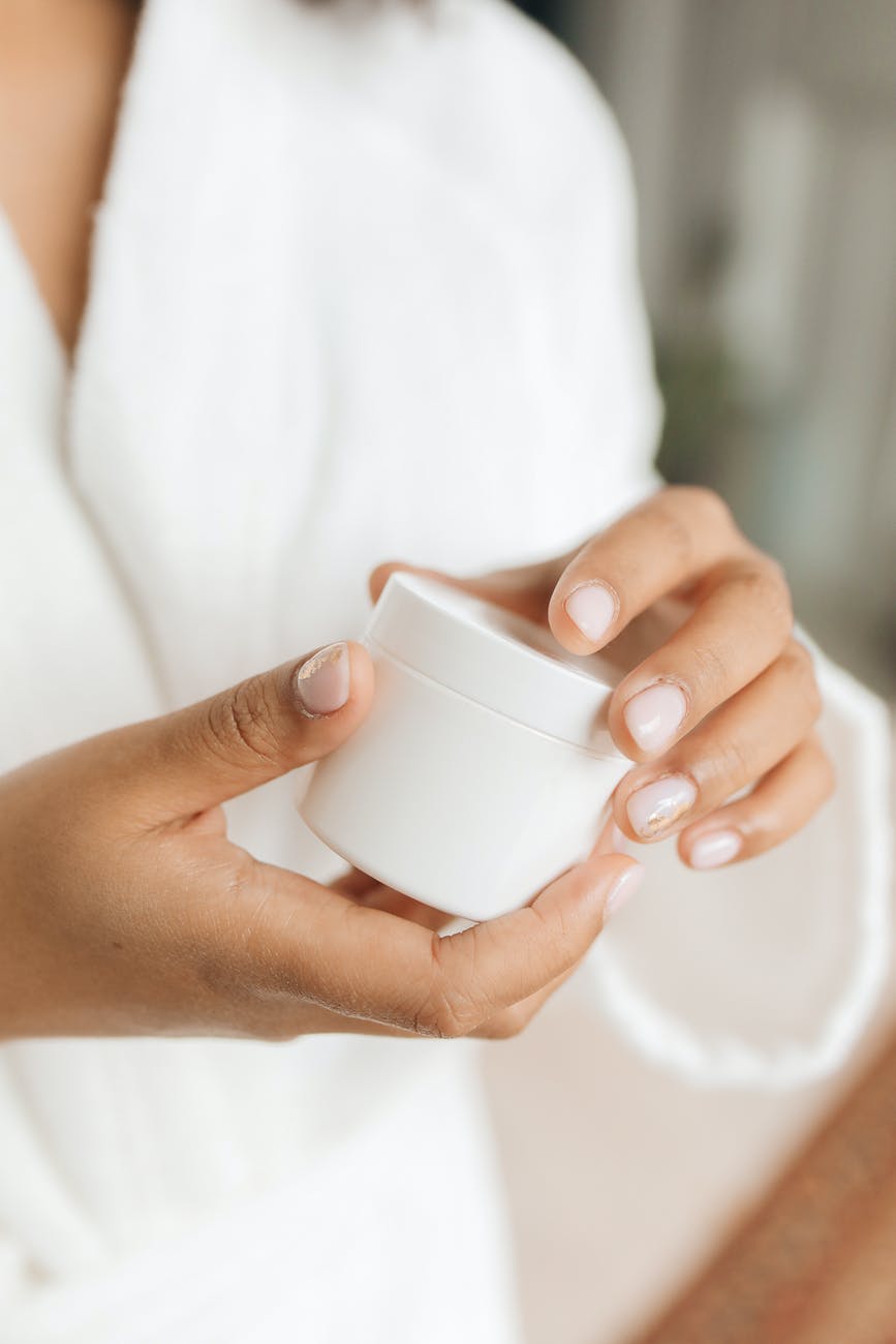 person holding white makeup container