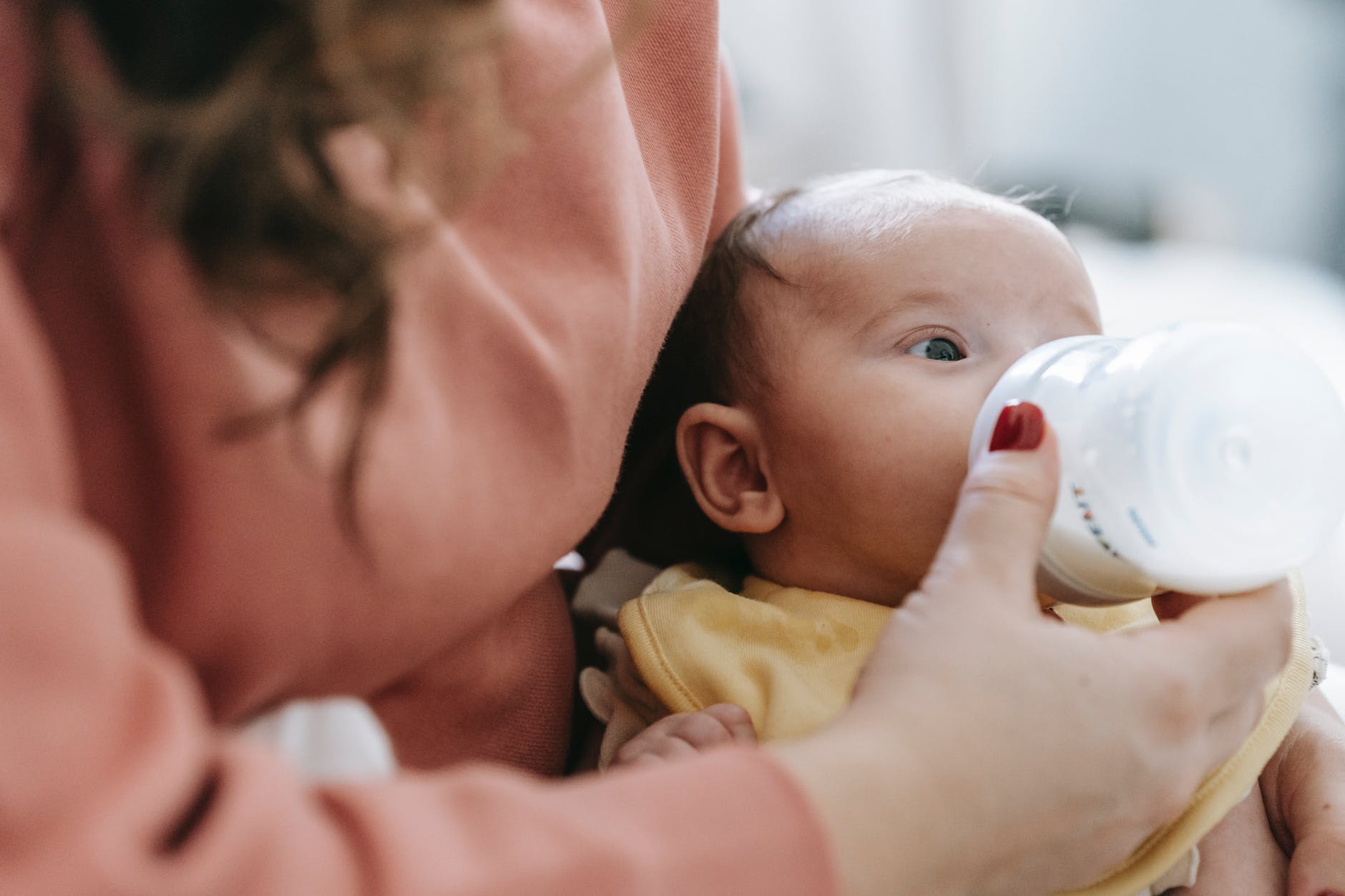 crop mother feeding infant with milk from bottle