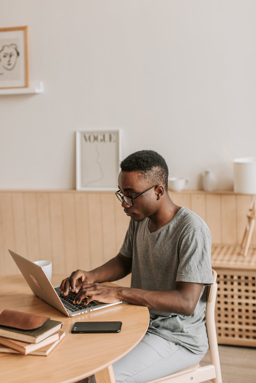 man in gray t shirt typing on laptop