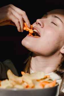 young woman eating salty popcorn with closed eyes