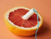 sliced ripe grapefruit with tampon against orange background